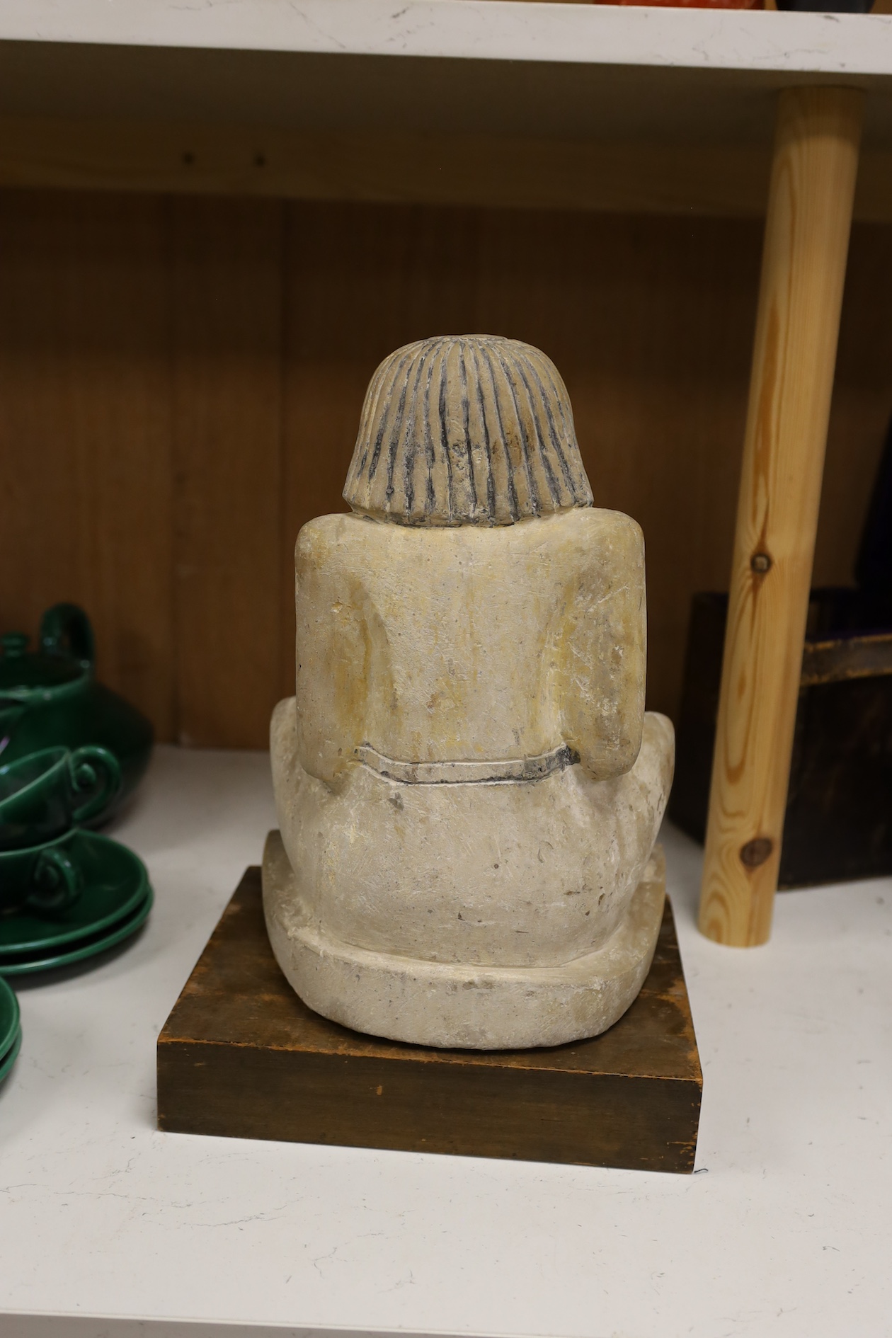 A carved stone Egyptian seated figure on wooden stand, 30cm high not including stand. Condition - fair to good